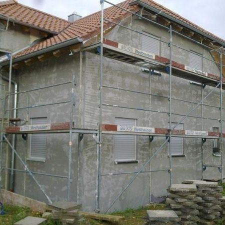 Baustelle mit Gerüst, wo man am Außenputz arbeitet